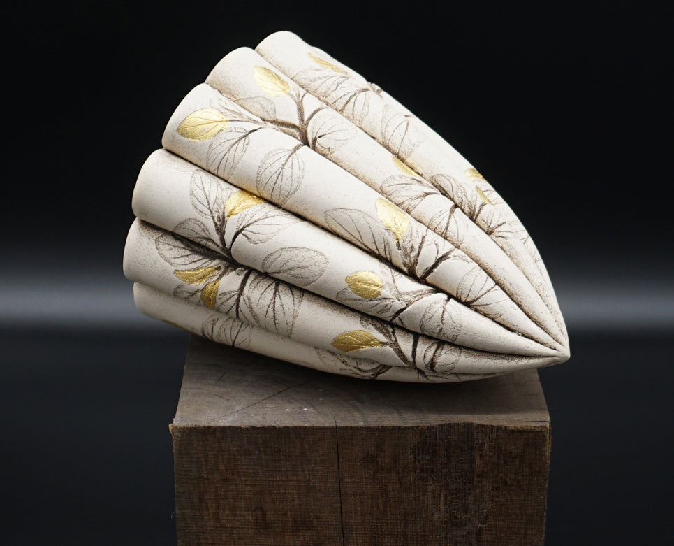 Original ceramic by Lisa Ellul.    Seedpods were the inspiration for this piece. Leaves have been rolled onto the surface of the clay leaving behind a skeletal imprint, almost like the fossilized wing of a dragonfly. Some leaves have been highlighted with 24ct gold leaf.  The pod is 15cm in length and constructed from white earthenware clay and fired to 1120 degrees Celsius.