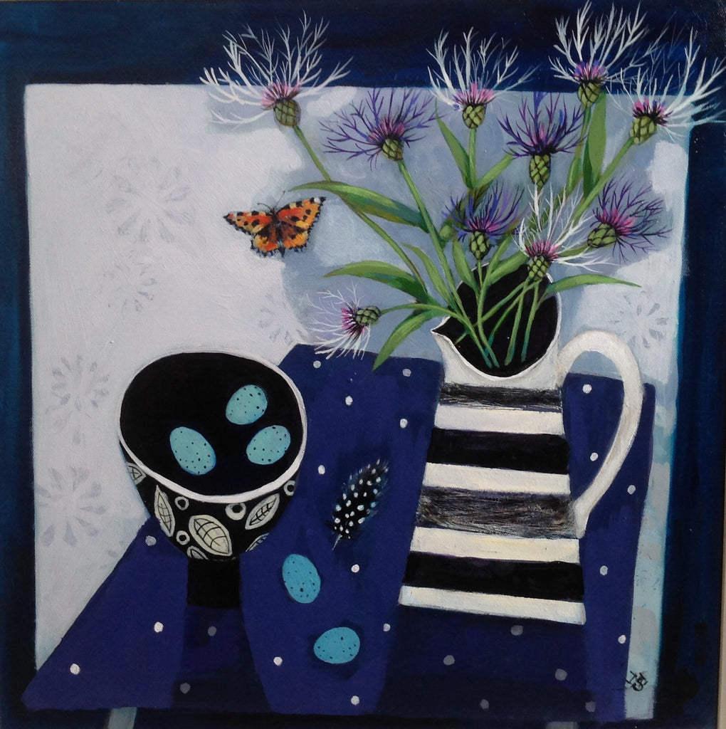 Attractive Still Live paining with tortoiseshell butterfly flying next to black and white striped jug displaying cornflowers with black and white small bowl holding blue bird eggs, standing on blue cloth with white dots